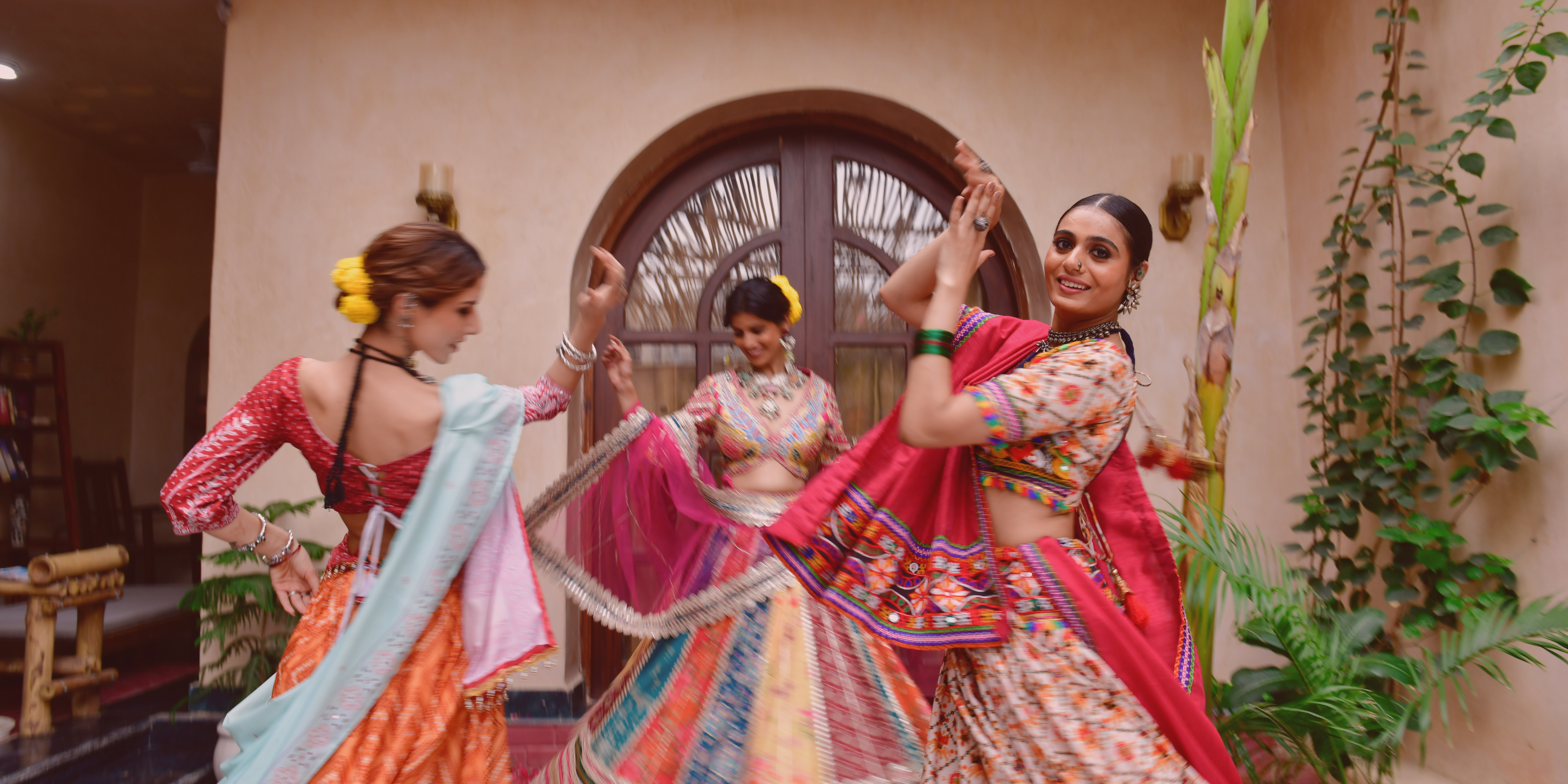 Photo of three young women dong garba indoors.