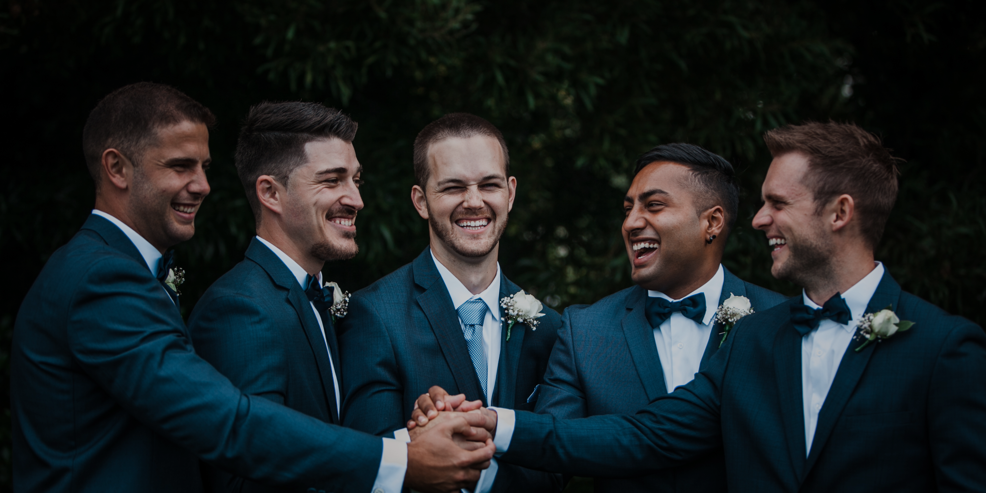 4 groomsmen standing next to the groom. The groom being in the center